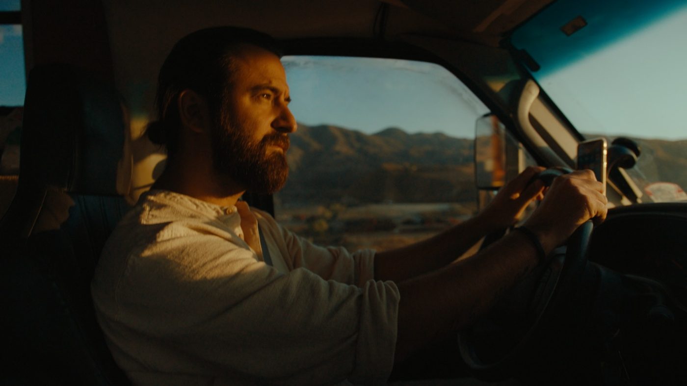 Philip at the wheel of the bus, desert hills through the window