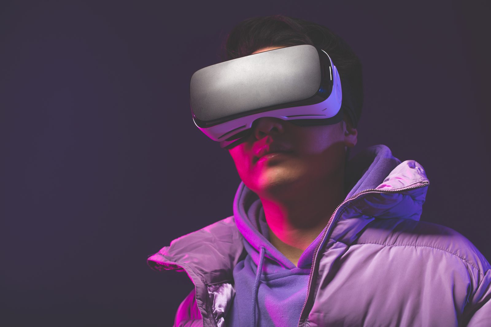 A person wearing a VR headset, lit in pink and violet