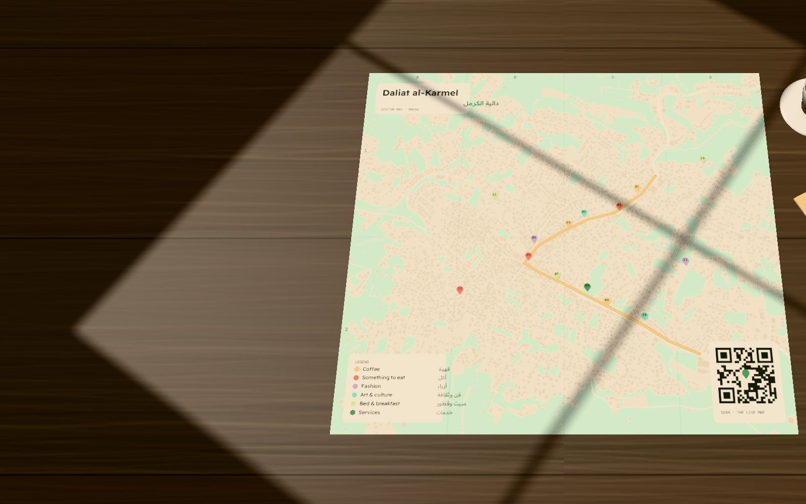 The printed Makan visitor map of Daliat al-Karmel, unfolded on a café table beside an espresso cup